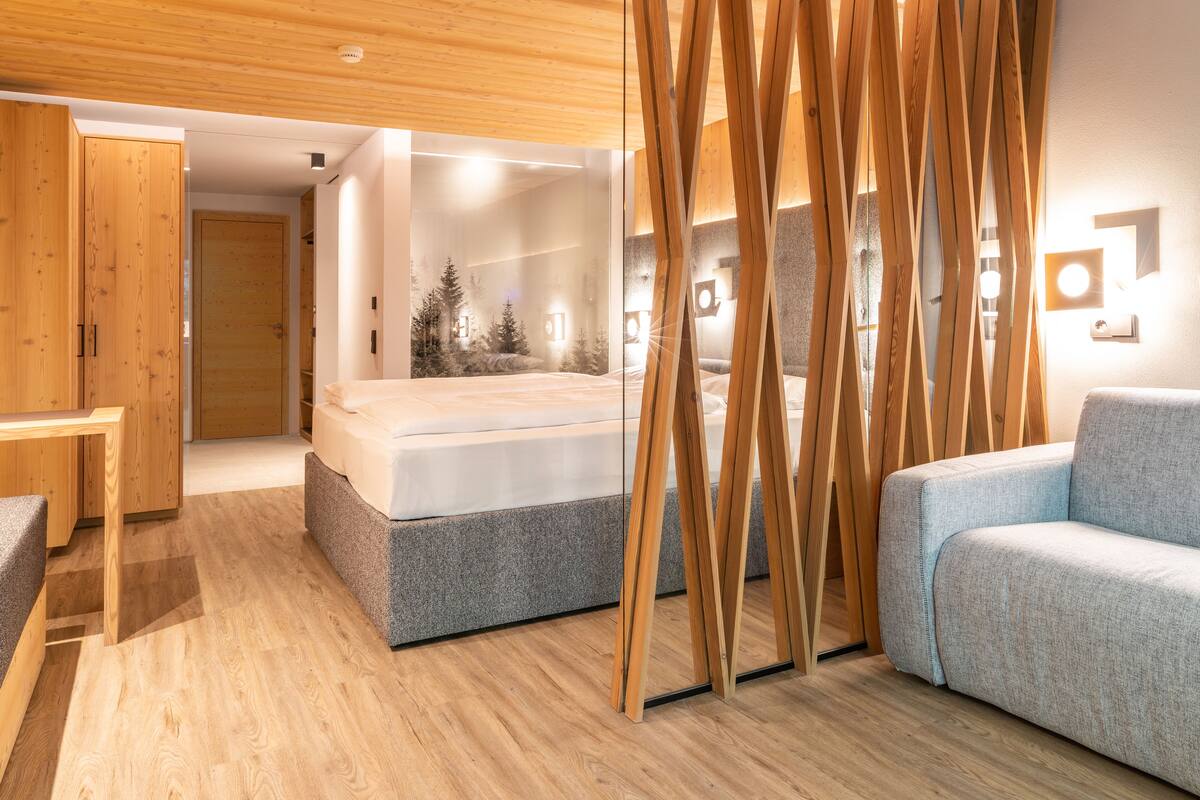 A modern bedroom with a bed, a sofa, and a wooden partition.