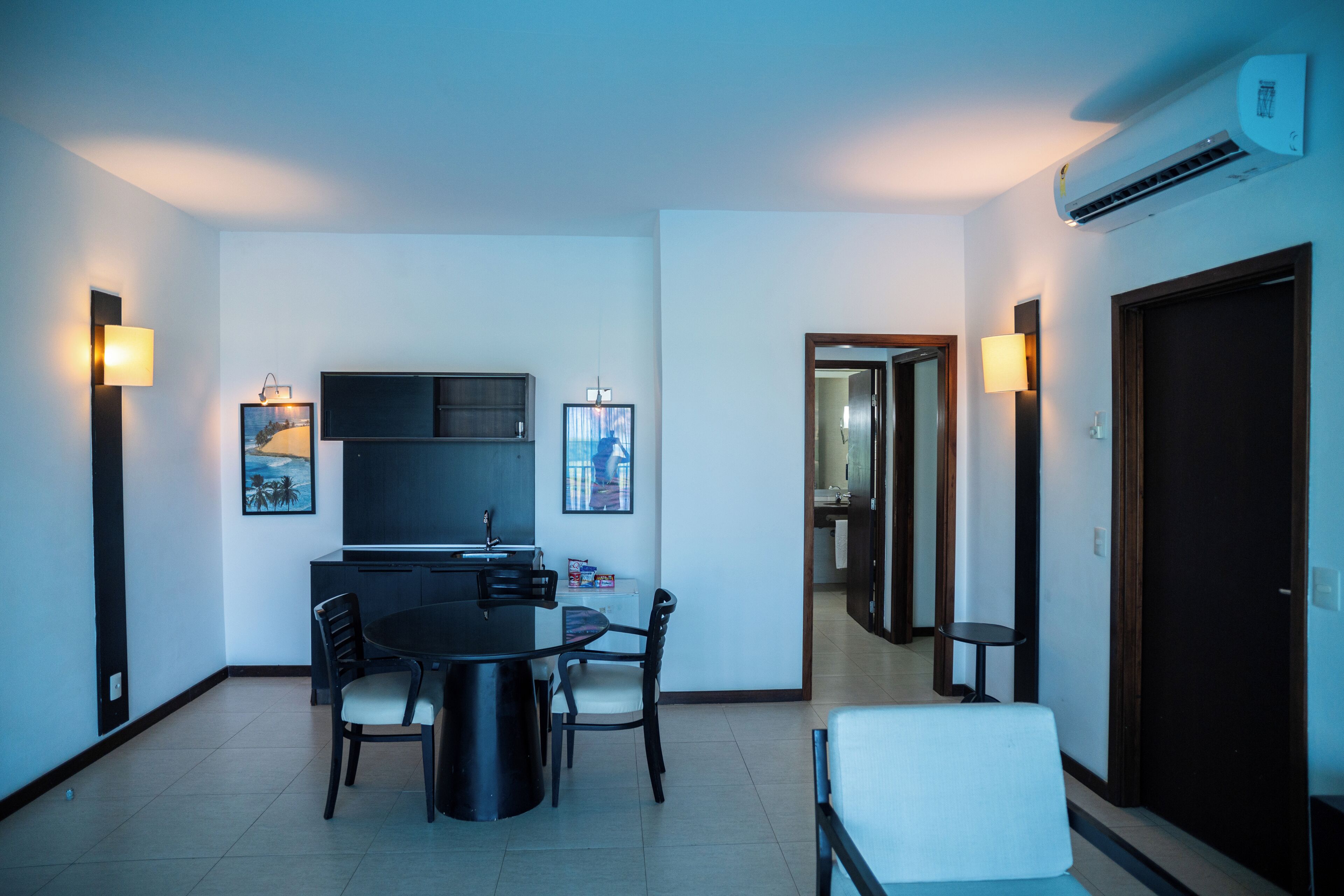 A modern living room with a dining area, a flat-screen TV, and a built-in air conditioner.