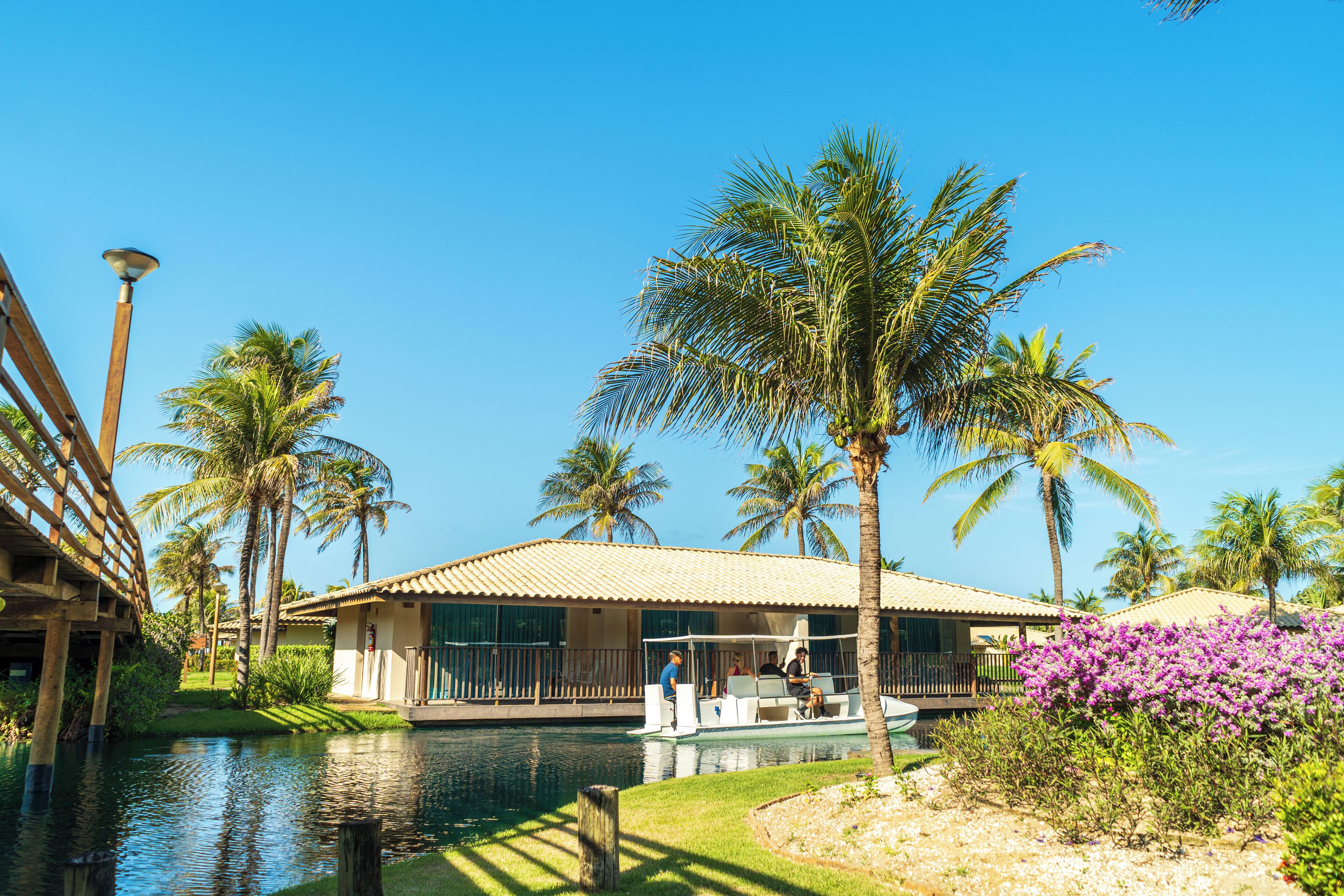 A resort with a pool, palm trees, and a building with a tiled roof.