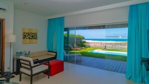 A modern living room with a large sliding glass door leading to a balcony with a pool and beach view. - Dom Pedro Laguna Beach Resort & Golf by WAM Experience (Aquiraz)
