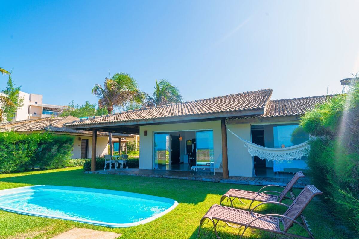 A house with a swimming pool, a hammock, and a patio with chairs.