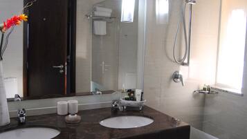 A bathroom with two sinks, a large mirror, and a shower.