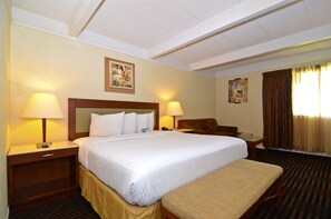 A hotel room with a large bed, two bedside tables with lamps, a chair, a desk, and a window with curtains. - Lexington Inn & Suites NW Chicago Elgin (Elgin)