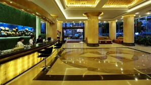A hotel lobby with a reception desk, bar seating, large columns, and a decorative wall with flowers. - Hongfeng Hotel Shenzhen (Shenzhen)