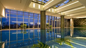A modern indoor swimming pool with a city view, large windows, and a skylight. - Ningbo Nanyuan Universe Deluxe Hotel (Ningbo)