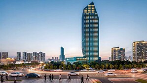 A modern high-rise building with a unique angular design, surrounded by a busy urban street with cars and pedestrians. - Ningbo Nanyuan Universe Deluxe Hotel (Ningbo)