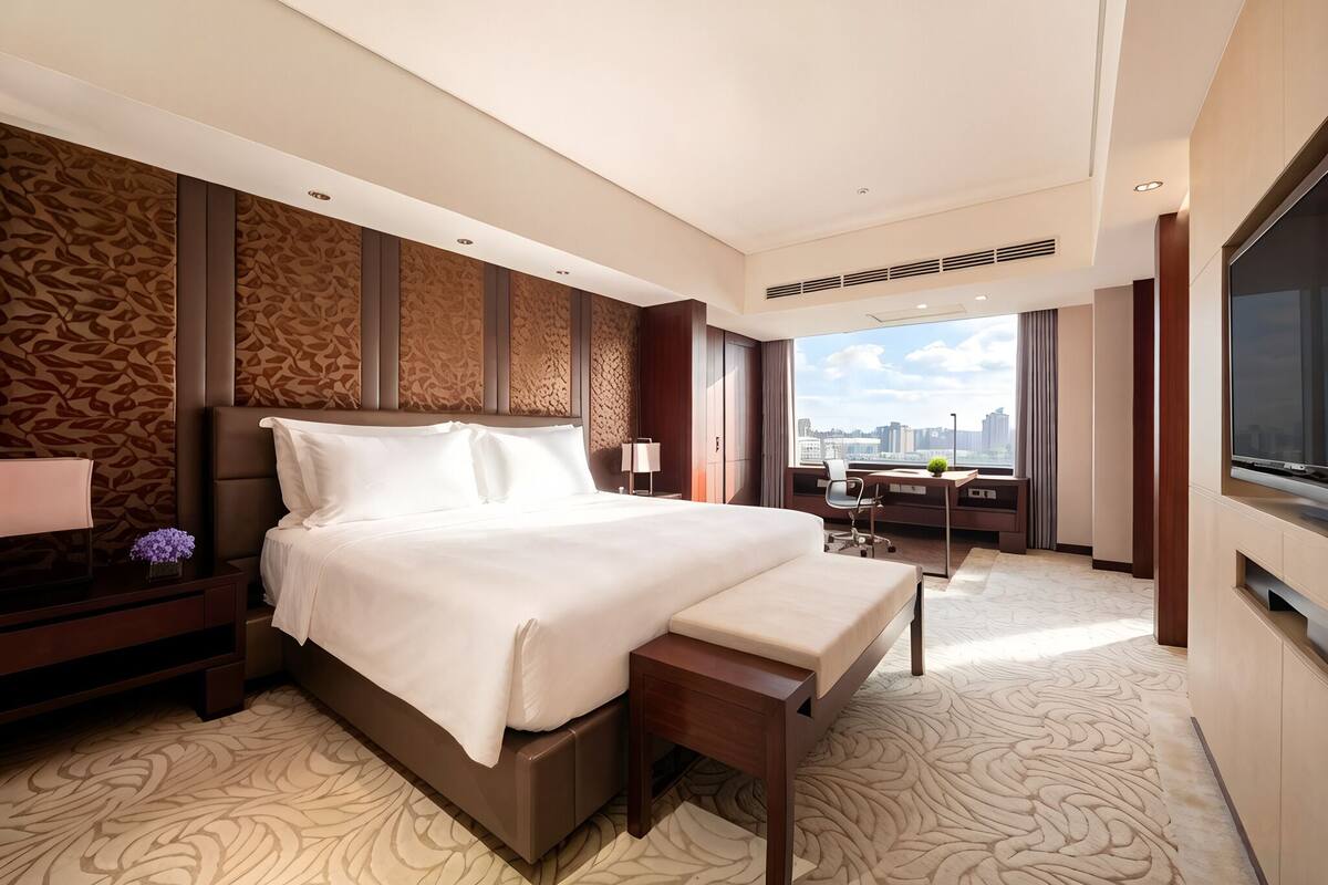 Een moderne hotelkamer met een groot bed, een bureau, een stoel, een televisie en uitzicht over de stad.