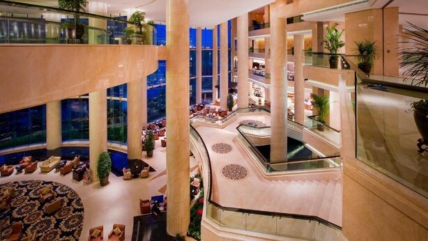 A multi-level hotel lobby with a central atrium, glass railings, and multiple seating areas. - Ningbo Nanyuan Universe Deluxe Hotel (Ningbo)