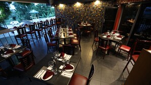 Een restaurant met meerdere tafels voor diners, met zowel zitbanken als gewone stoelen.