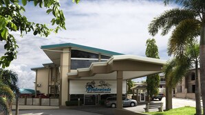 Een hotel met een modern design, met een overdekte ingang, een trap en een parkeerplaats.
