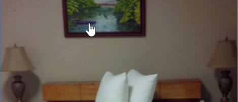 A hotel room with a bed, two nightstands, a painting of a landscape, and a telephone on the nightstand.