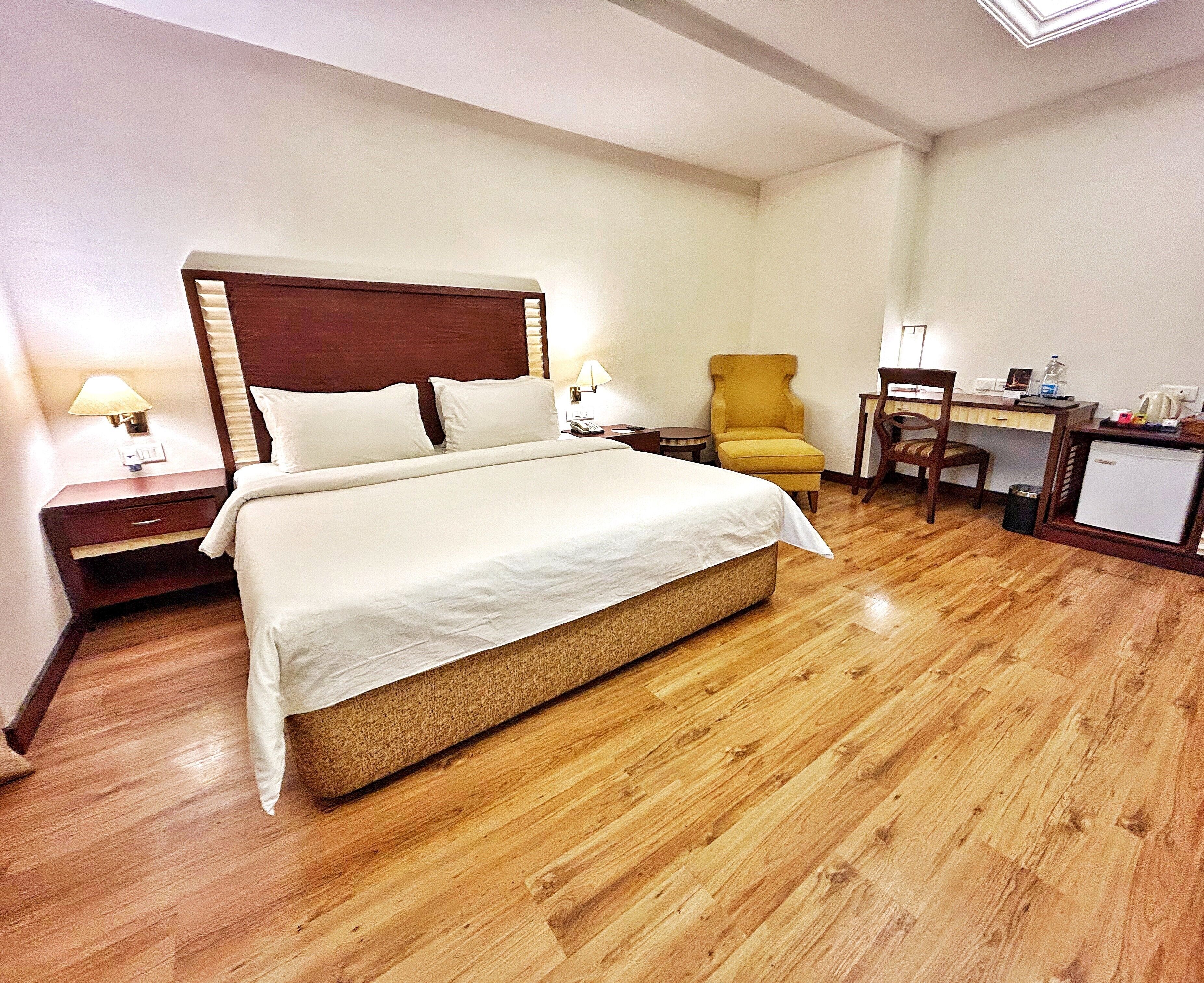 Una habitación de hotel con una cama grande, un escritorio, una silla y una mesita de noche.