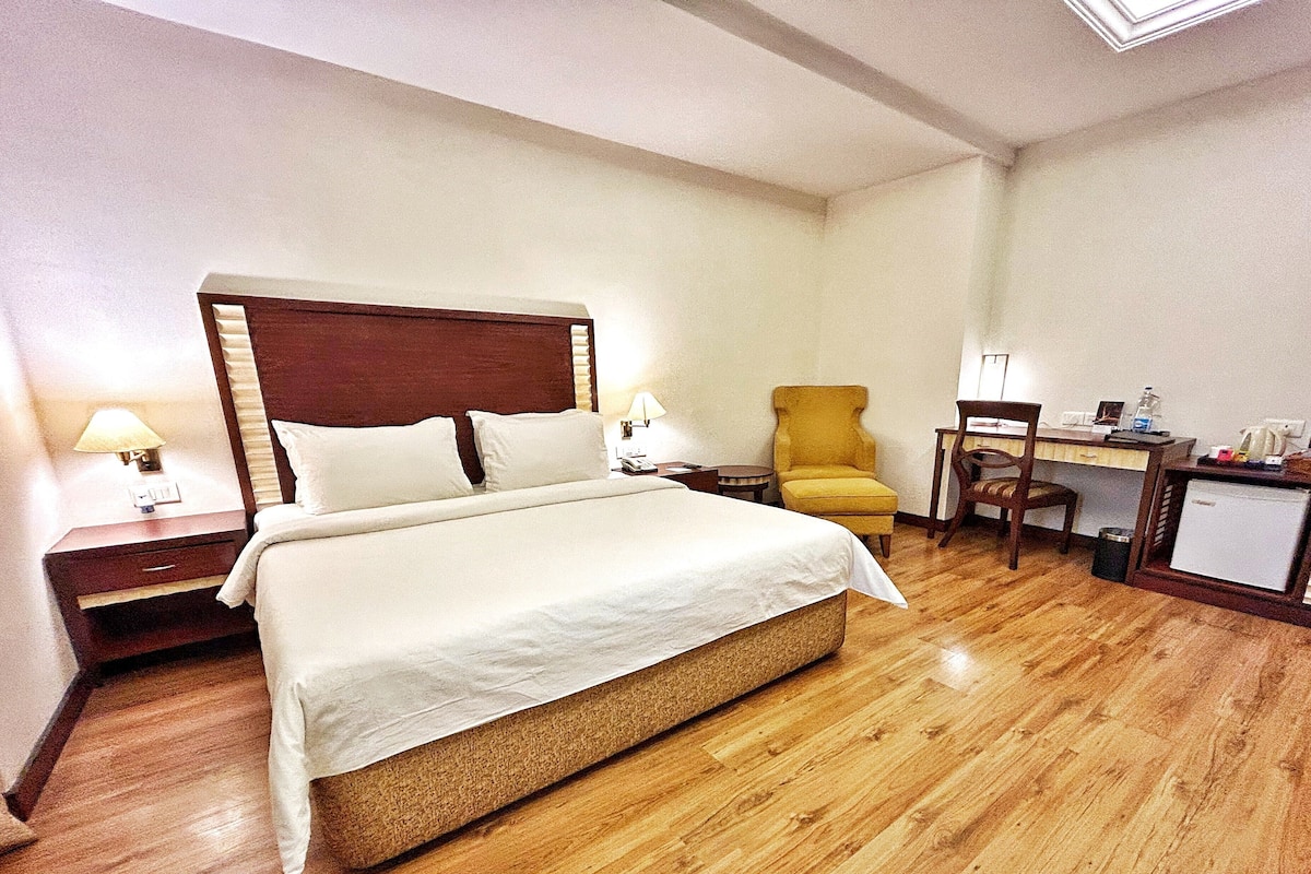 Una habitación de hotel con una cama grande, un escritorio, una silla y una mesita de noche.