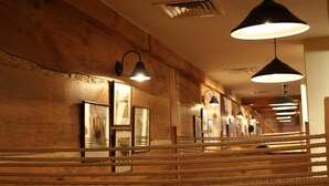 Interior de madera con barreras de cuerda, iluminación colgante y cuadros en la pared.