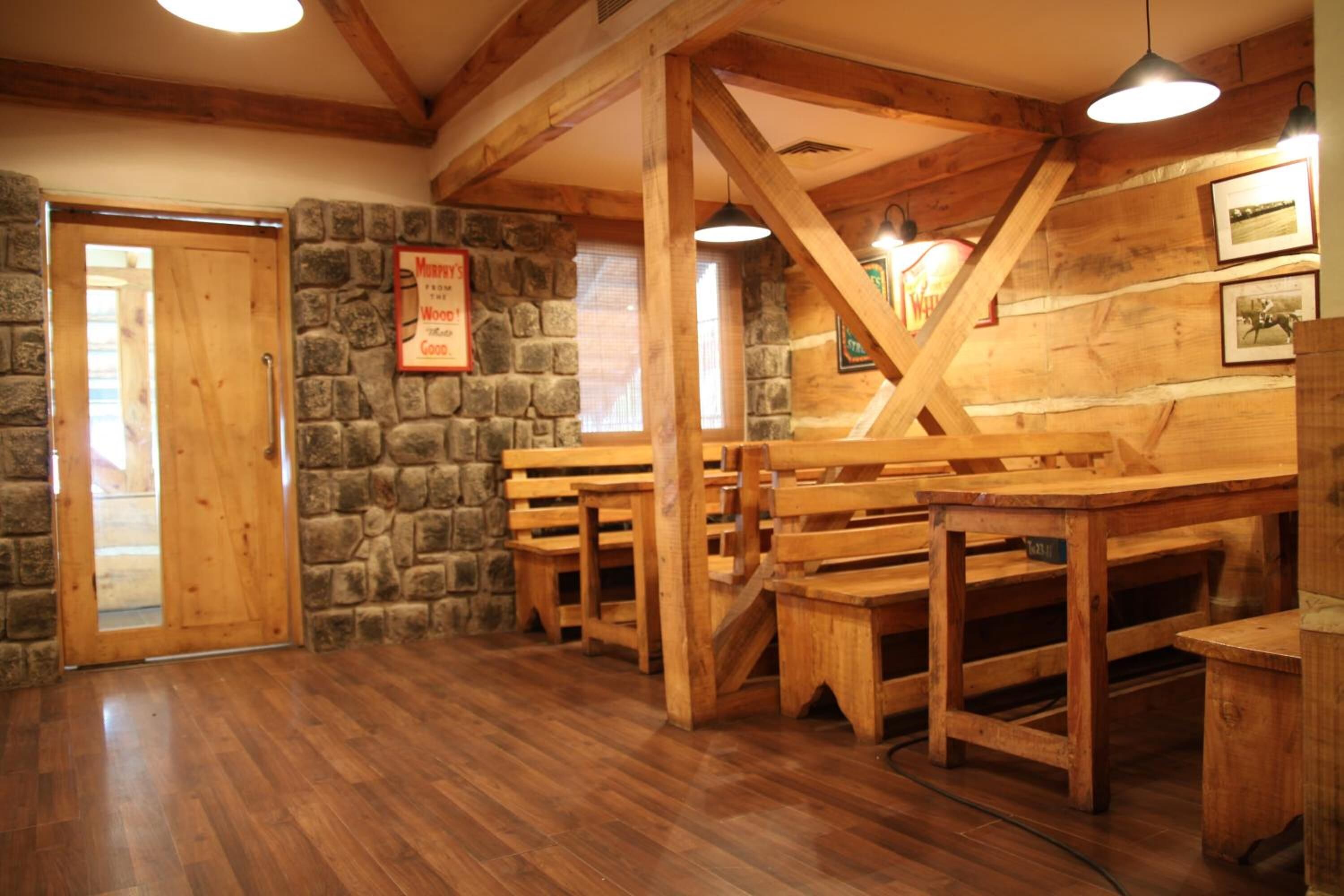 A rustic interior with wooden benches and stone walls, featuring a wooden door and a sign on the wall.