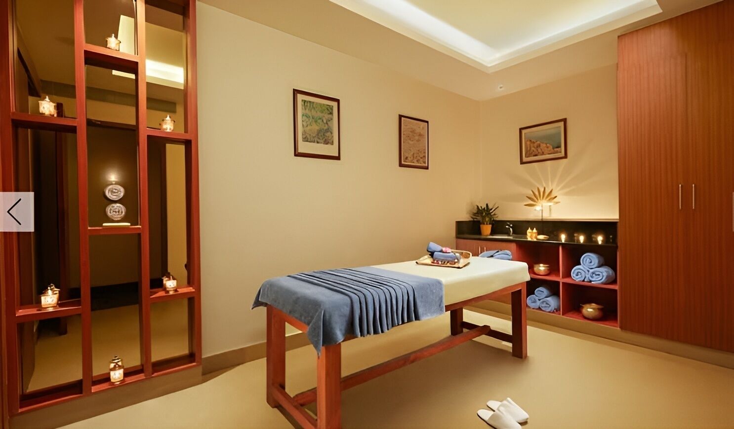 Een kamer met een massagetafel, planken met handdoeken en een kast.