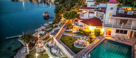 A resort with a swimming pool, outdoor seating, and a view of the water.