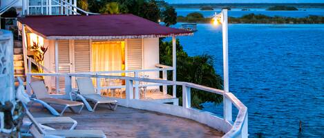 A beachfront property with a covered patio, lounge chairs, and a view of the ocean.