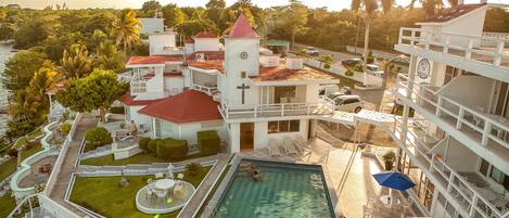 A hotel with a swimming pool, outdoor seating, and a view of the surrounding landscape.