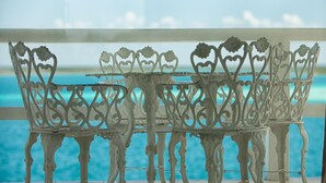 A white metal outdoor table and chairs with intricate designs, positioned near a window overlooking a body of water. - Hotel Laguna Bacalar (Bacalar)