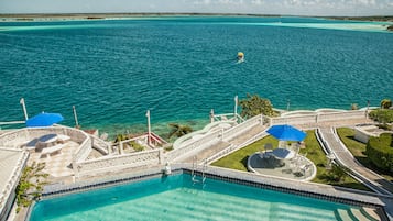 Relax by the infinity pool overlooking the turquoise sea, surrounded by comfortable lounge chairs and umbrellas.
