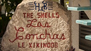 Egy kőtábla, amelyen piros és kék betűkkel a következő felirat olvasható: „The Shells Las Palmas Le Xikinoob”.