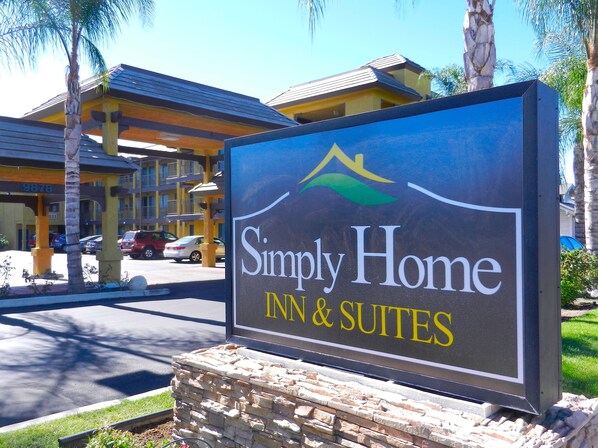 A sign for Simply Home Inn & Suites with a mountain and palm tree logo.
