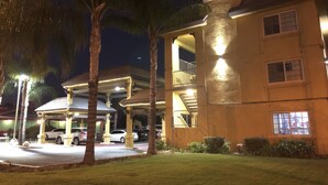 A hotel with a covered outdoor area, palm trees, and a well-lit building facade. - Simply Home Inn & Suites (Riverside)