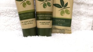 Three toiletry bottles with olive oil fragrance on a white towel. - Simply Home Inn & Suites (Riverside)