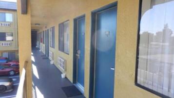 Une rangée de portes bleues sur un bâtiment jaune, avec un parking visible à l’arrière-plan.