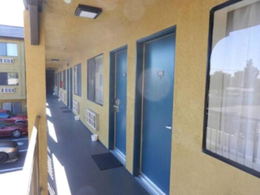 Une rangée de portes bleues sur un bâtiment jaune, avec un parking visible à l’arrière-plan.