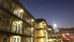 A multi-story building with balconies and illuminated windows at night. - Simply Home Inn & Suites (Riverside)