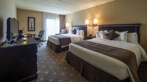 Quarto de hotel com duas camas, uma escrivaninha, uma cadeira e uma televisão.