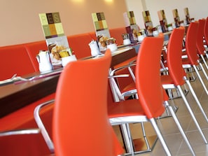 A restaurant with red chairs and tables, each with a menu stand displaying food options. - ibis Gloucester (Gloucester)