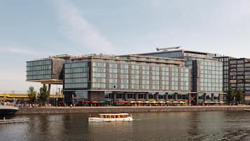 A modern hotel with a glass facade, a waterfront view, and a boat dock.