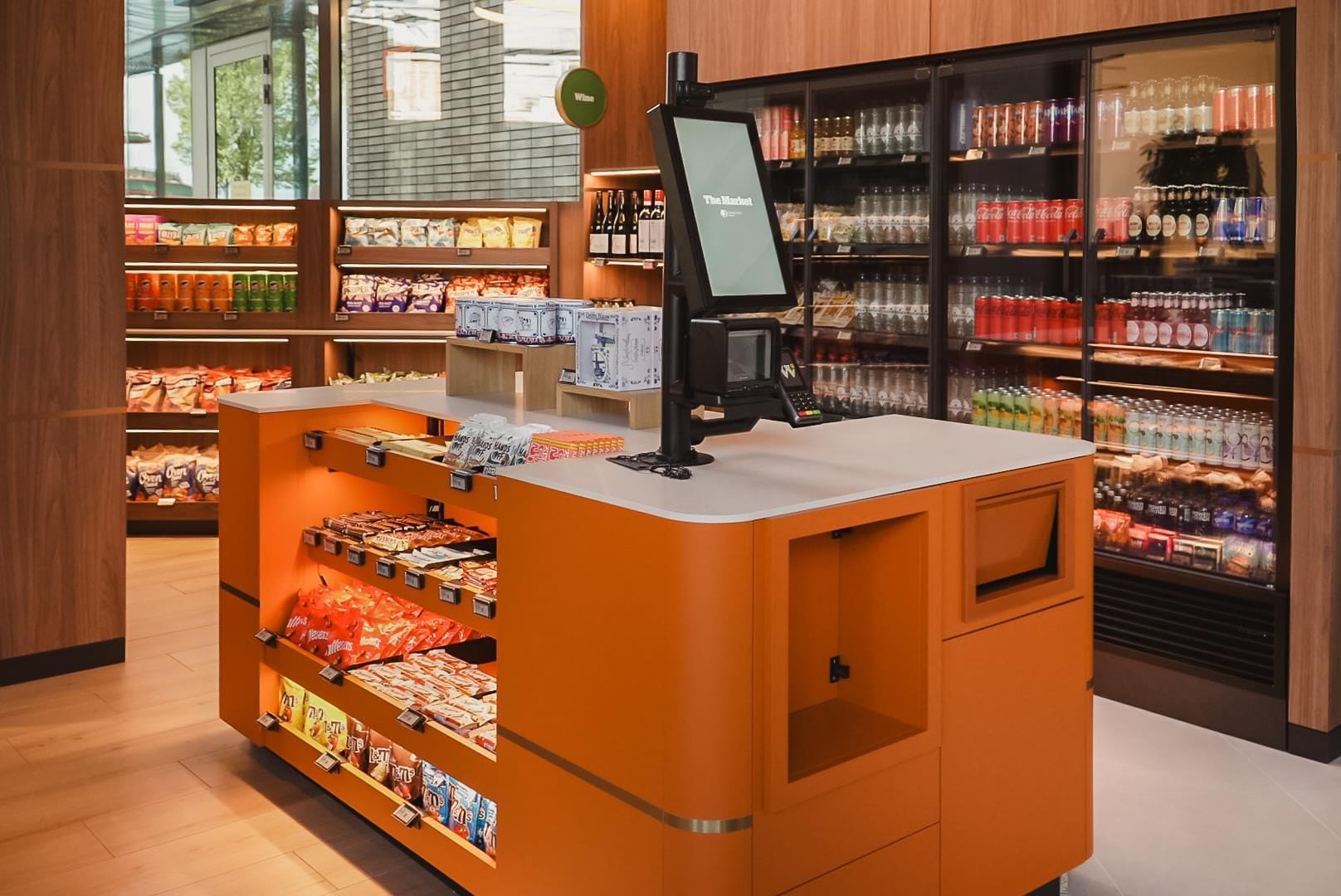 A self-service kiosk with a digital screen, surrounded by shelves stocked with snacks and beverages.
