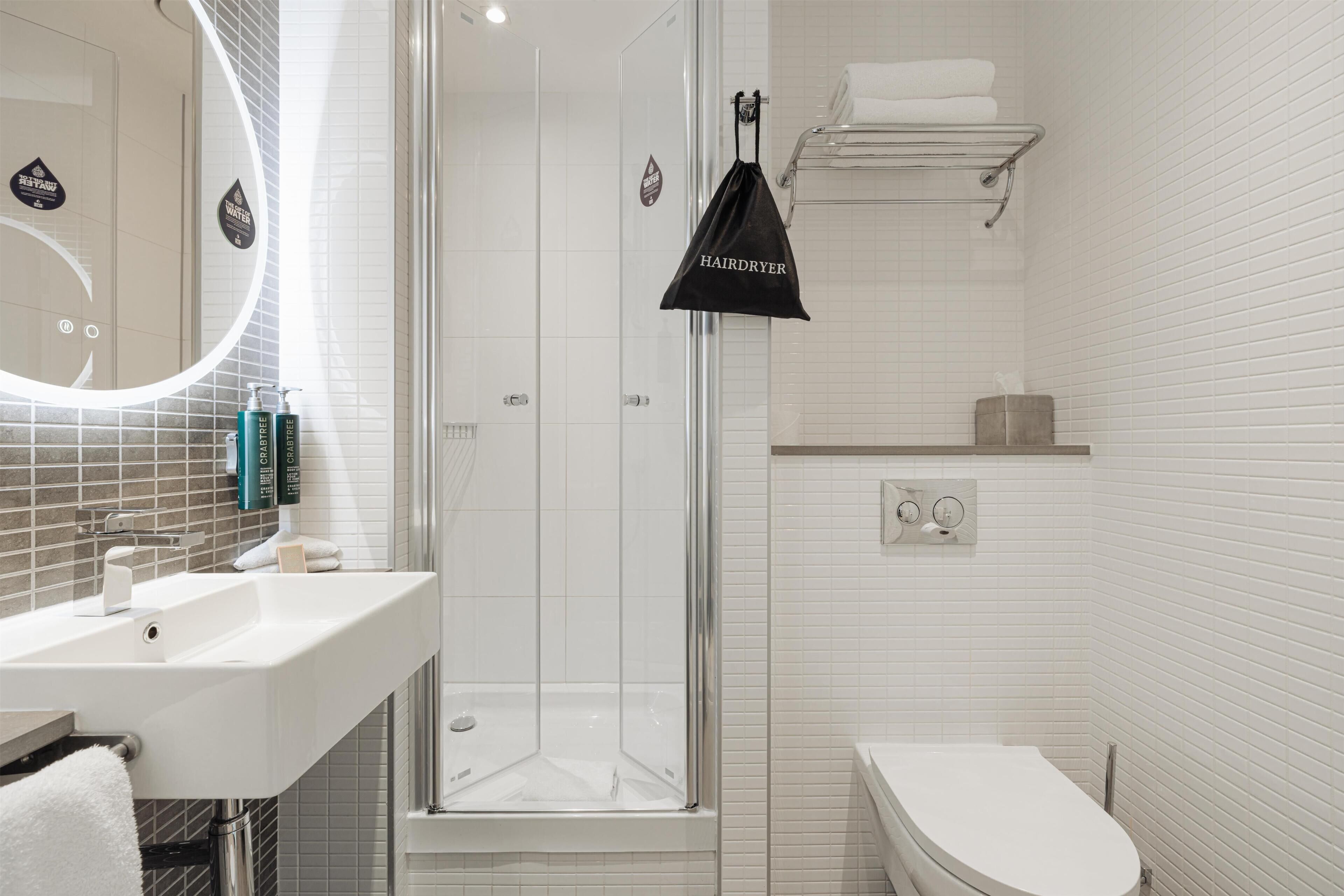 A modern bathroom with a glass-enclosed shower, a white sink, and a toilet.