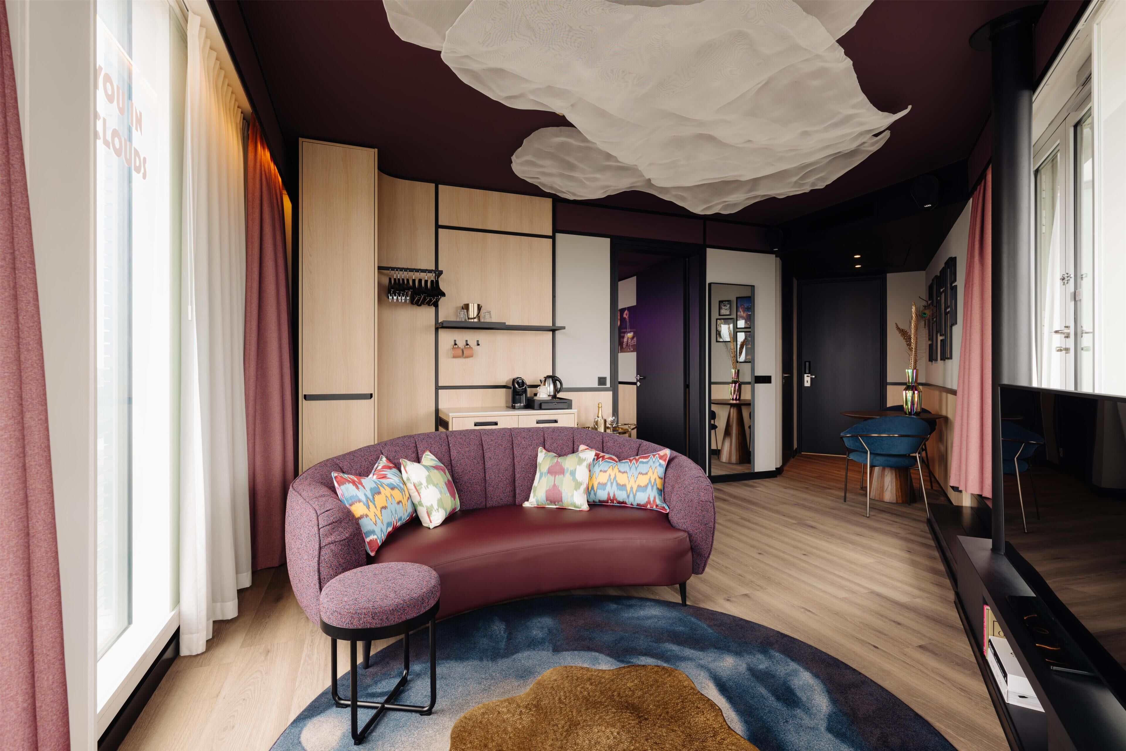 Un salon moderne avec un canapé aux lignes courbes, une petite table et un tapis décoratif.