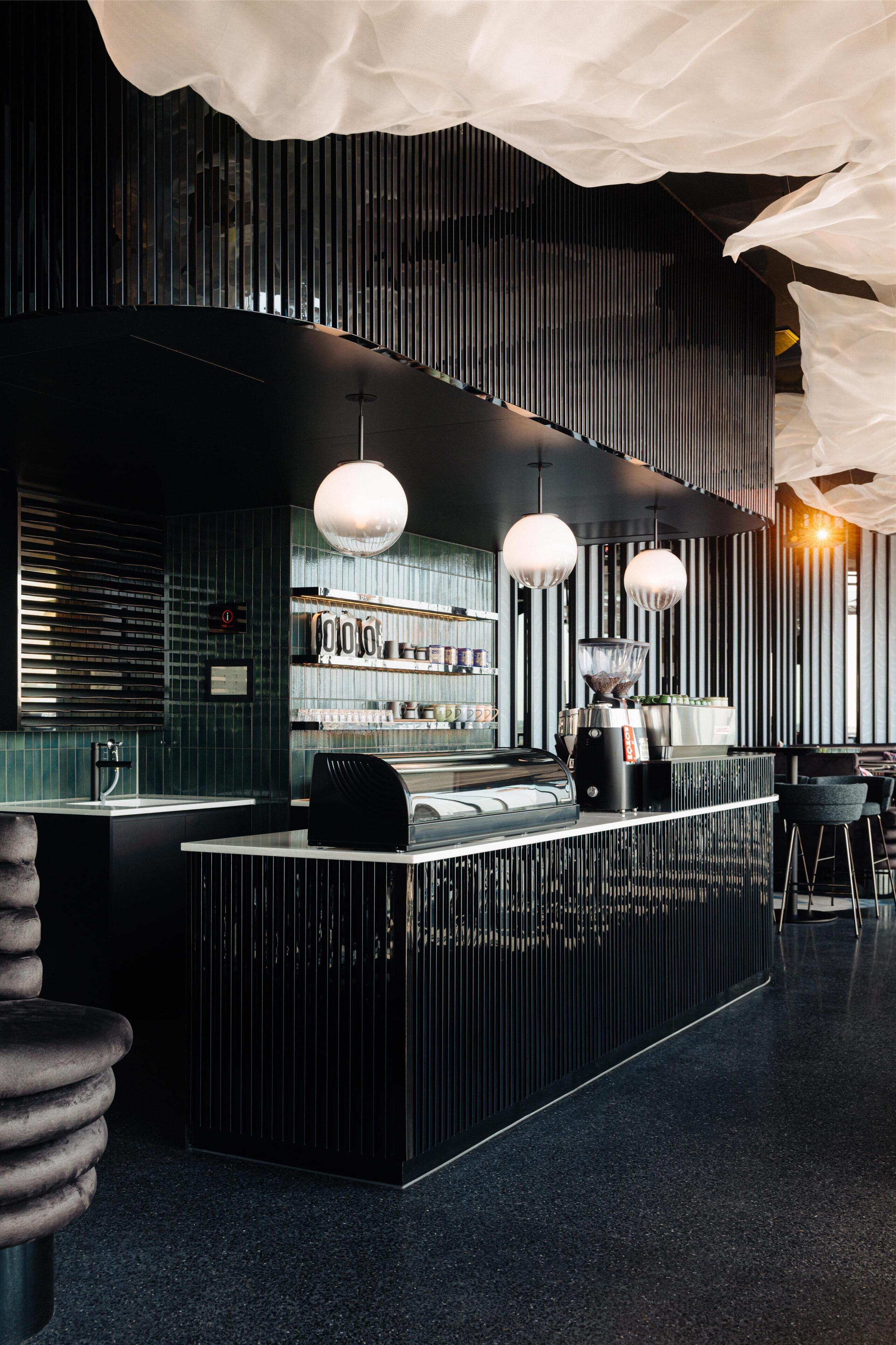Un espace bar moderne avec un comptoir, des tabourets de bar et des luminaires suspendus.