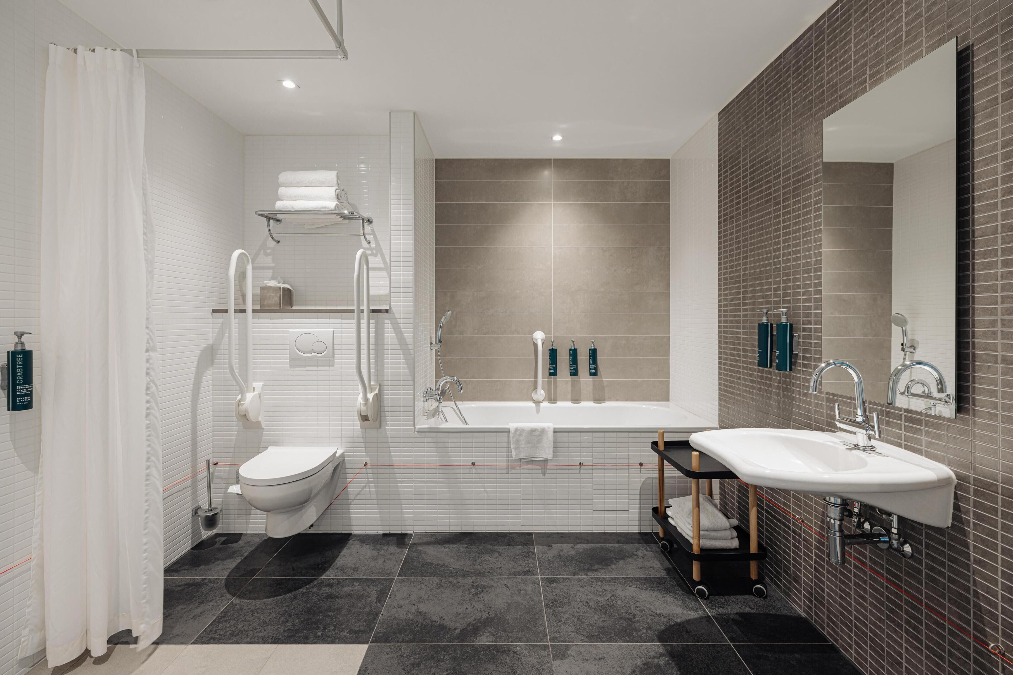 Une salle de bain moderne équipée de toilettes, d’un lavabo, d’une baignoire et d’une douche.