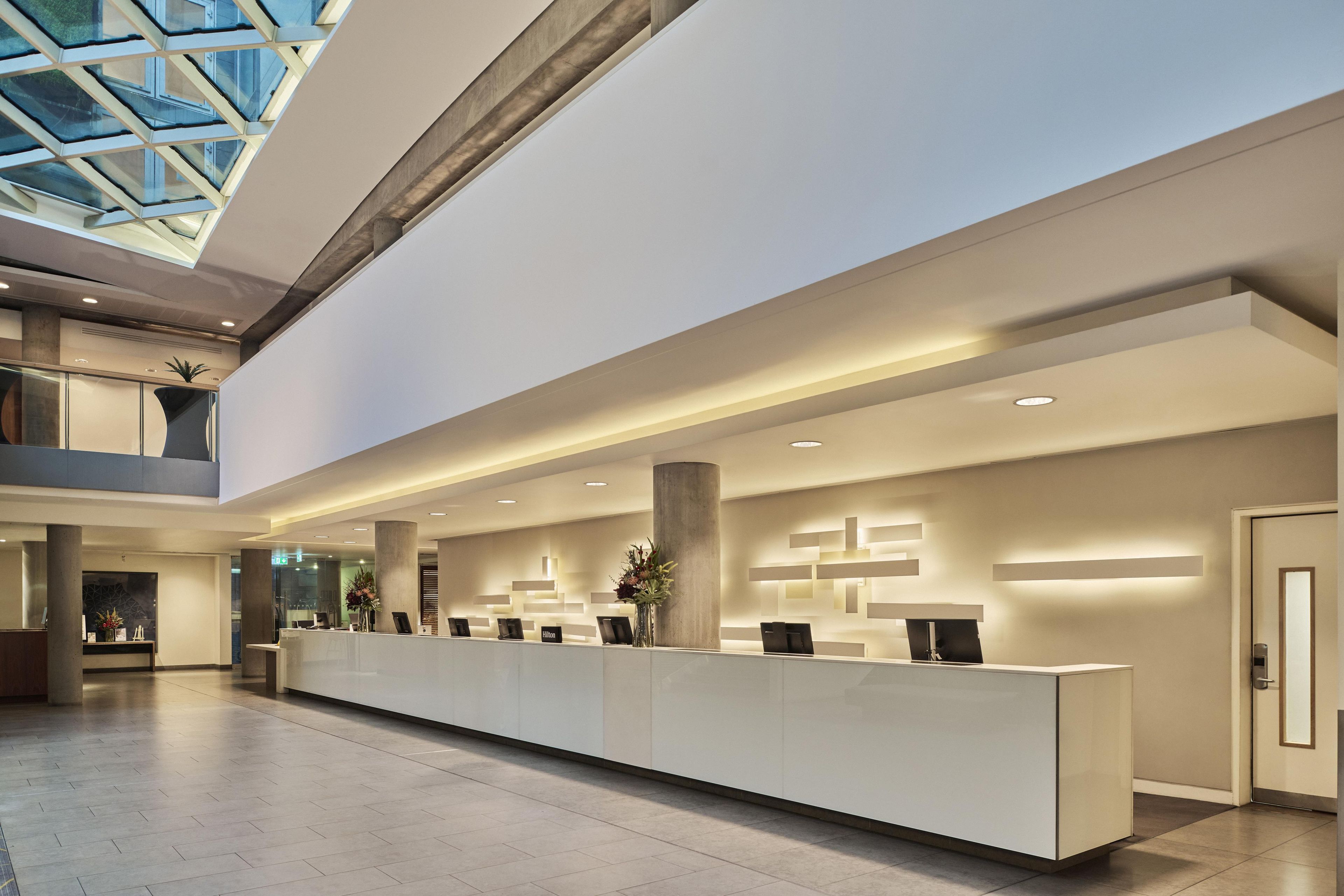 A modern reception area with a long counter, glass ceiling, and minimalist decor.