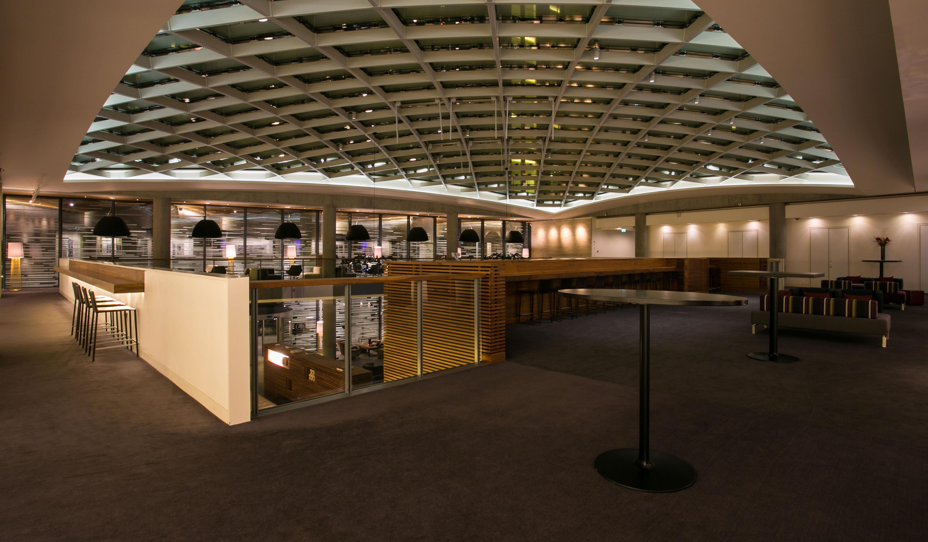 A modern interior with a central bar area, seating arrangements, and a high ceiling with skylights.