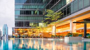 Een modern hotel met een dakterraszwembad, buitenzitplaatsen en een stadsachtergrond.