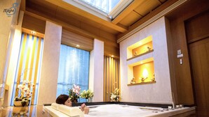 A spa room with a large bathtub, wooden ceiling, and decorative shelves with lights. - Sivatel Bangkok (Bangkok)