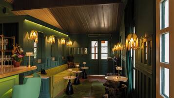 Une salle avec un coin bar, des sièges et des tables.