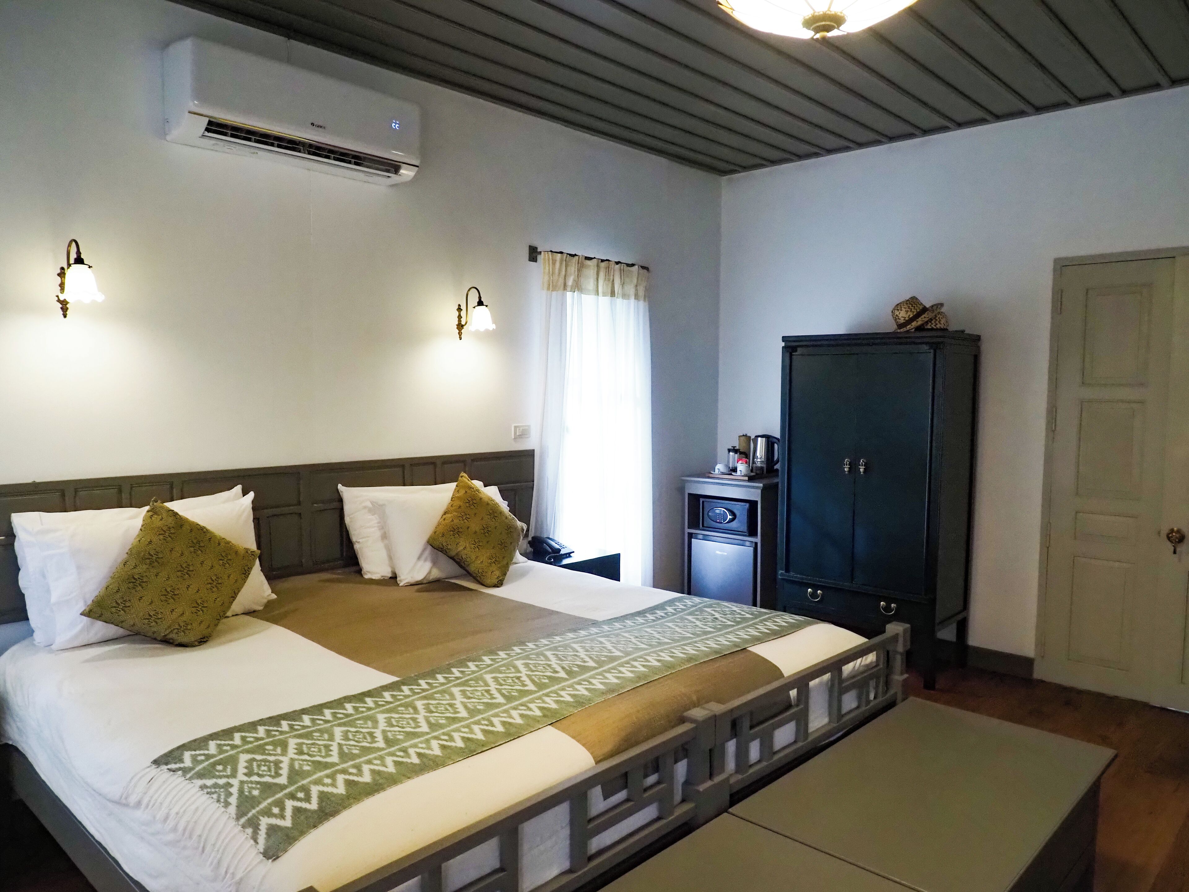 Habitación de hotel con cama, mesita de noche, armario y equipo de aire acondicionado.