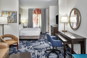 A hotel room with a bed, a desk, a chair, a TV, and a painting on the wall. - Fairfield Inn and Suites Gainesville (Gainesville)