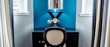 A room with a desk, chair, and a wall-mounted lamp.