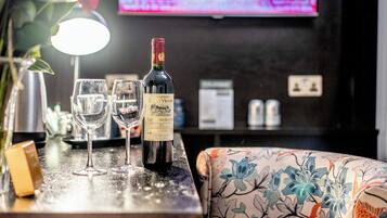 A bar area with a bottle of Chateau Jean Voisin wine, two glasses, and a floral-patterned chair.