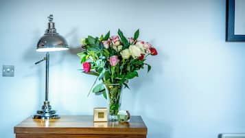 Ein Schreibtisch mit einer Lampe, einer Blumenvase und einer kleinen Schachtel.